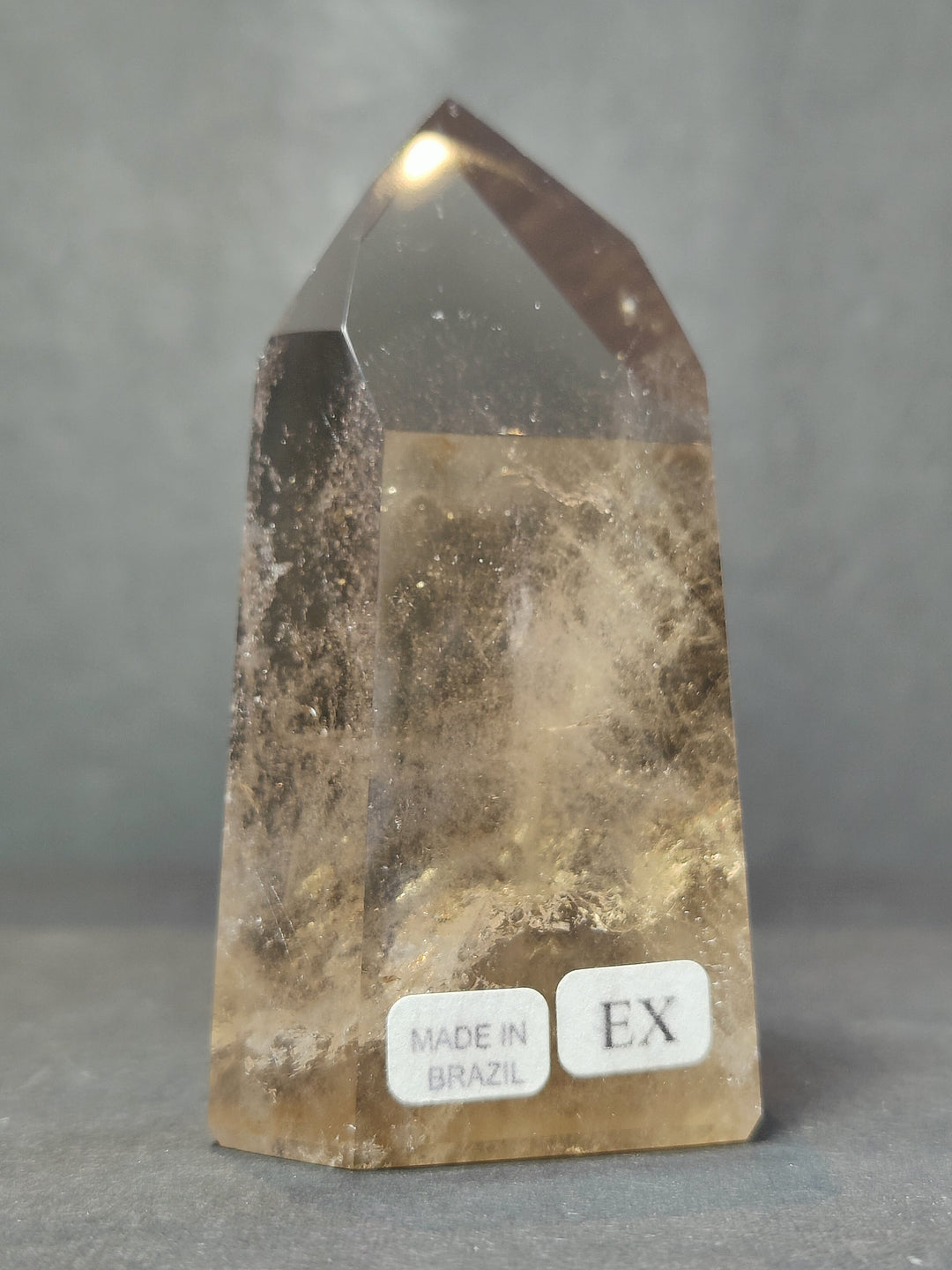 Smoky clear quartz free-form sculpture with glossy facets, labels: Made in Brazil and EX
