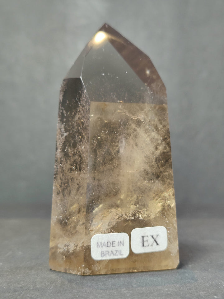 Smoky clear quartz free-form sculpture with glossy facets, labels: Made in Brazil and EX