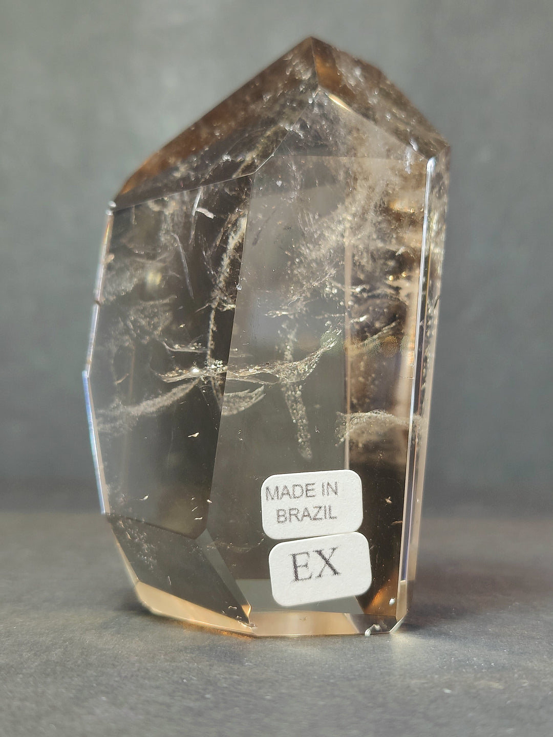 Clear smoky quartz free-form sculpture, faceted sides, labels: Made in Brazil and EX