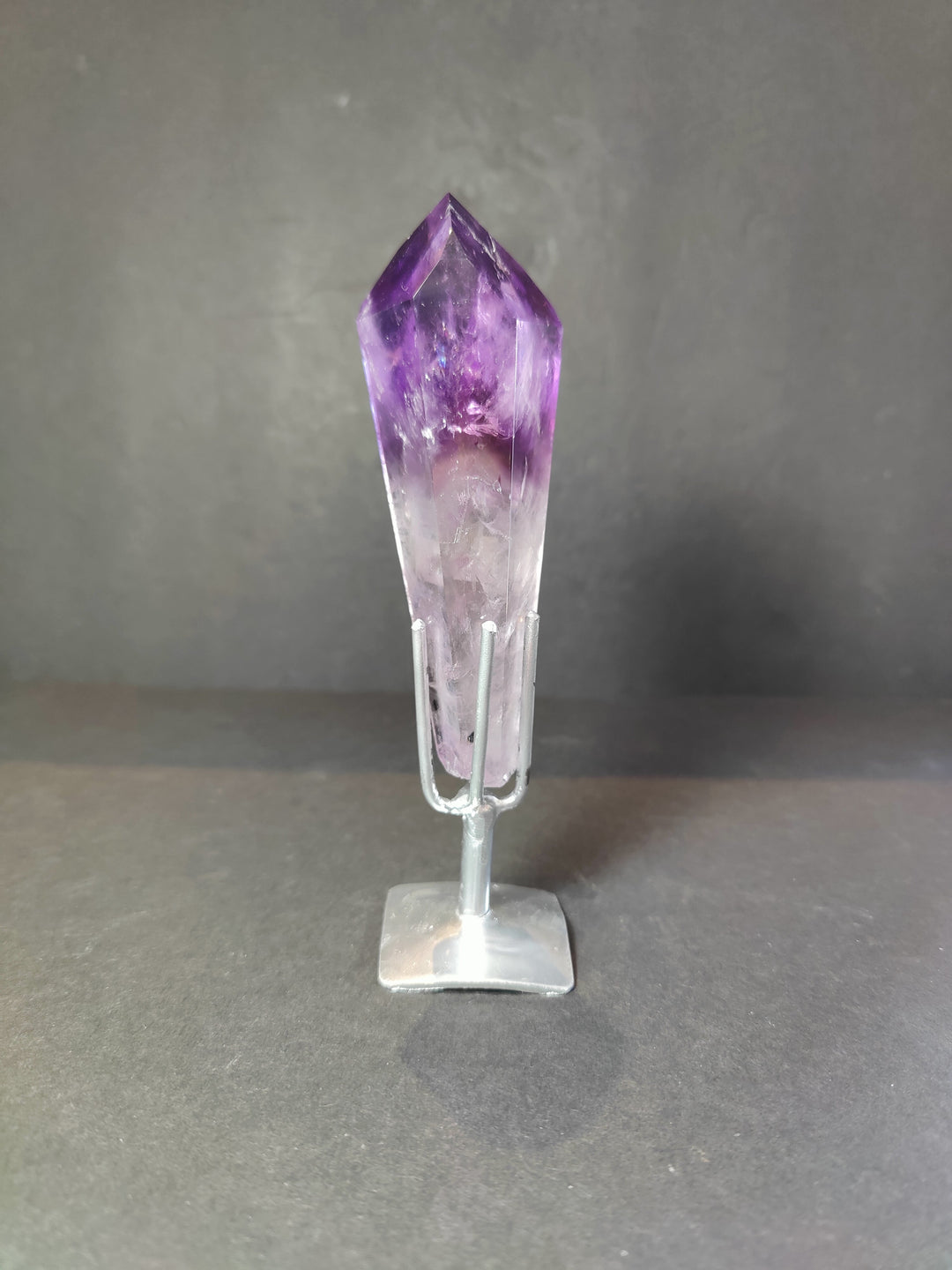 Single amethyst crystal scepter wand on clear metal stand, upright purple top