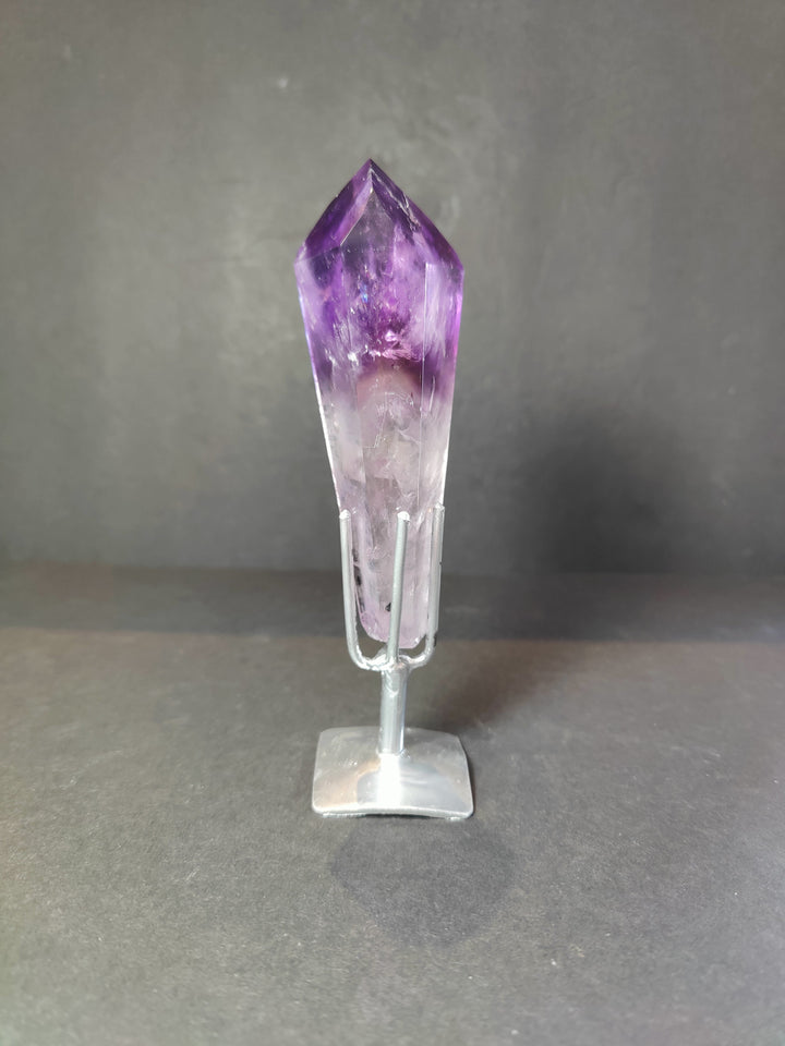 Single amethyst crystal scepter wand on clear metal stand, upright purple top