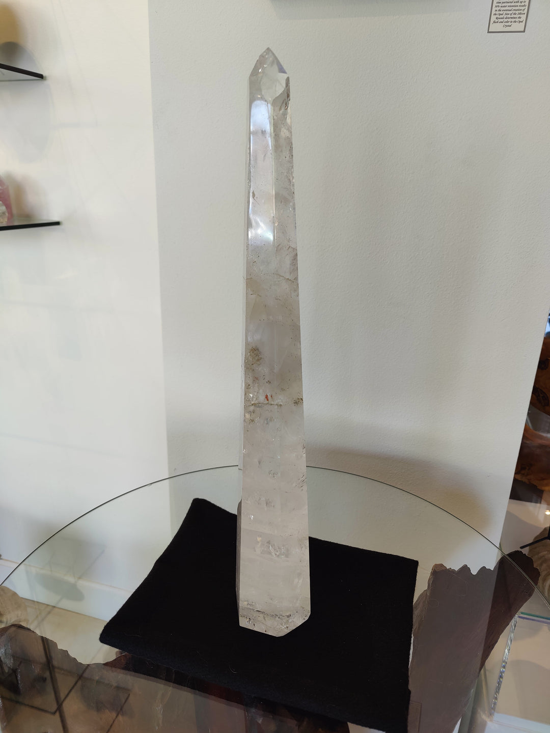 Polished clear quartz obelisk sculpture with pointed tip on black display base