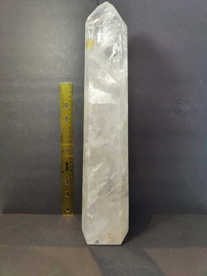 Polished clear quartz obelisk, tall faceted crystal with yellow measuring ruler for scale