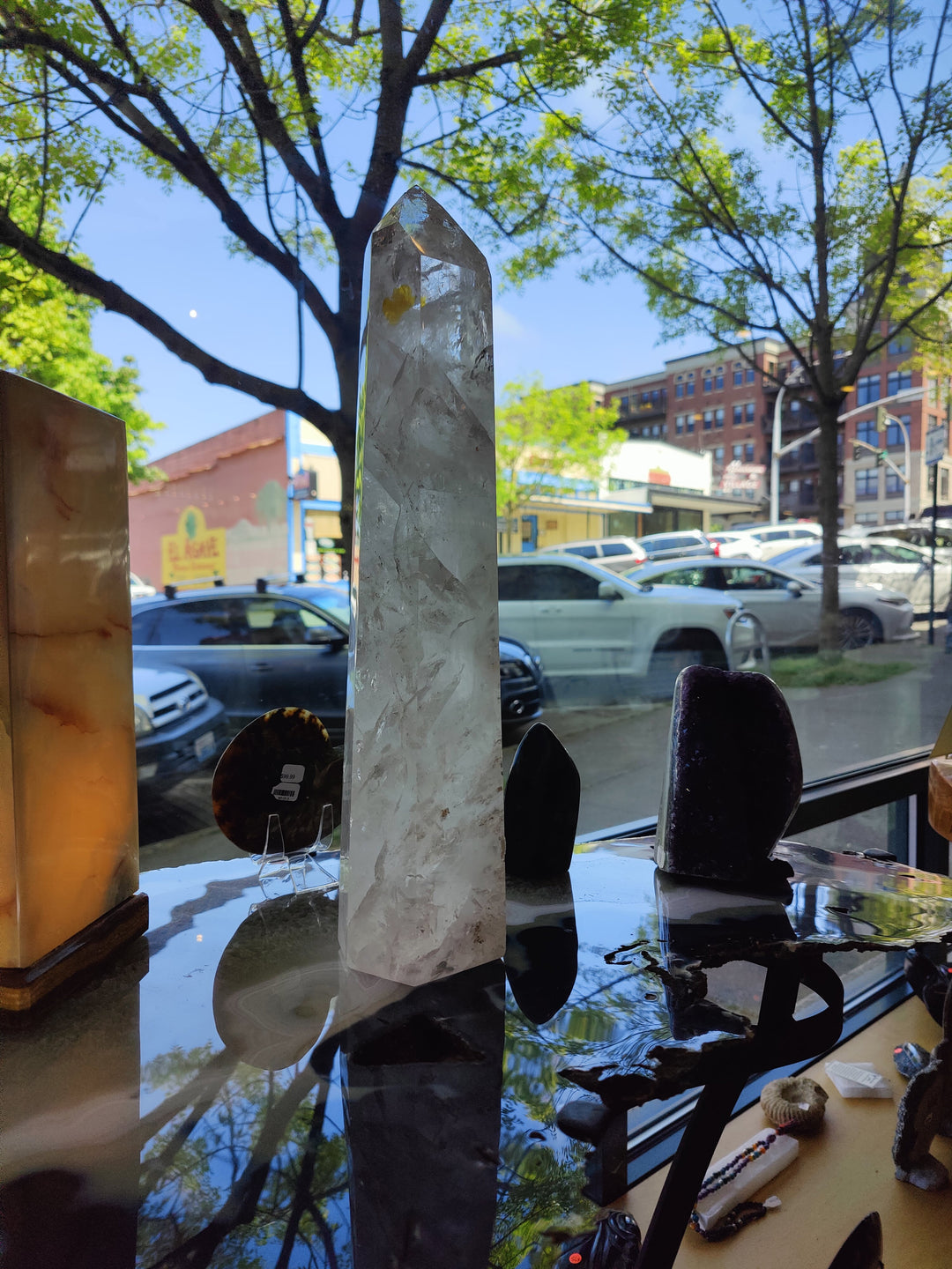 Polished clear quartz obelisk, tall faceted crystal with sharp pointed top and reflections