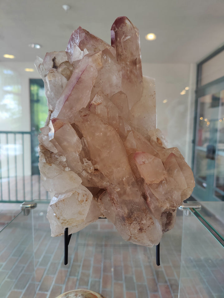 Pink and clear lithium quartz crystal cluster on black stand