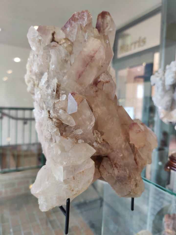 White and rose lithium quartz cluster with jagged points, on black stand