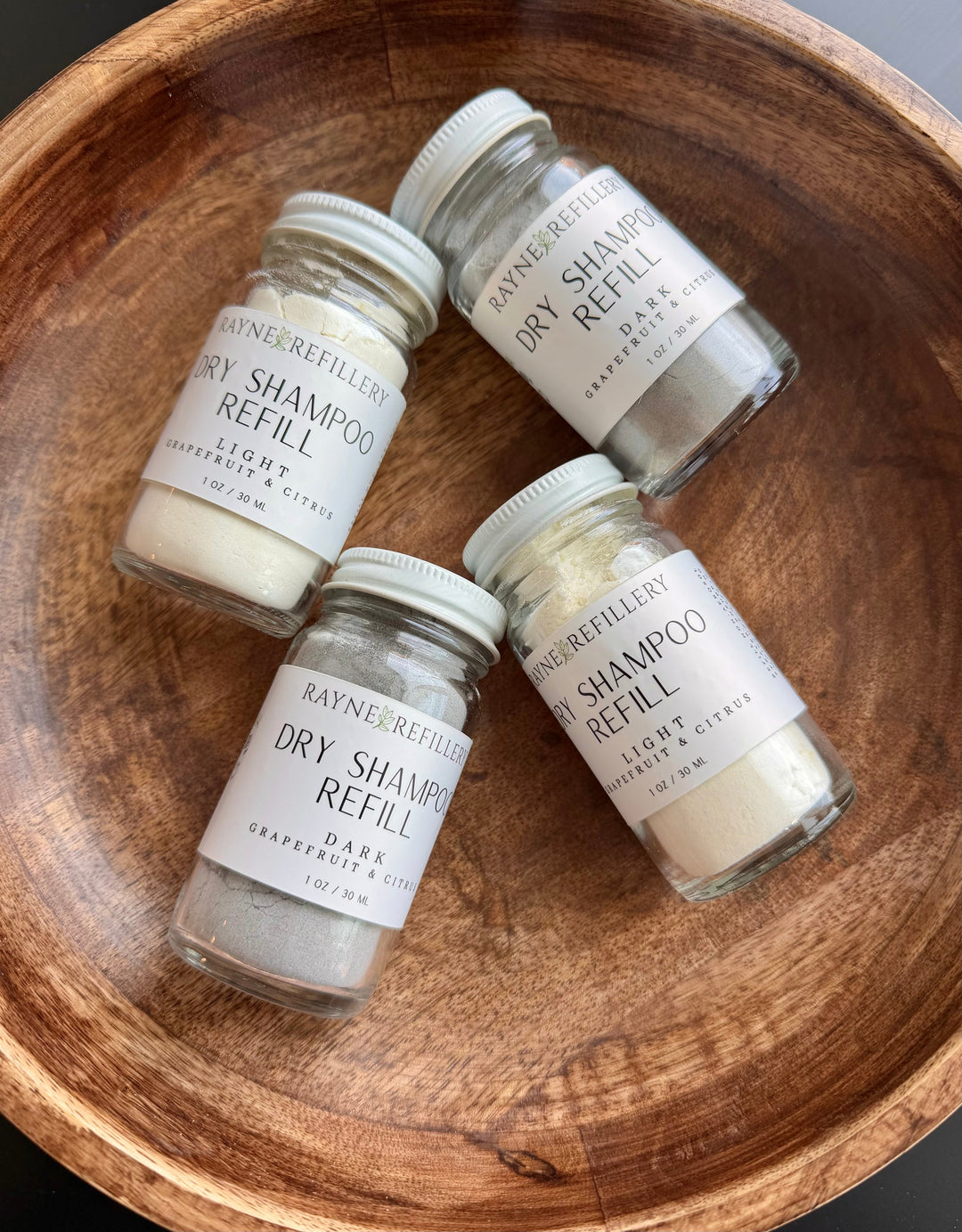 Dry shampoo refill canisters with white labels; multiple small clear bottles