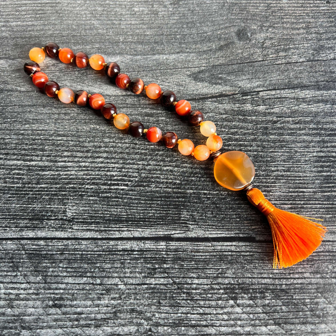 Orange and amber bead meditation mala with dark brown accents and orange tassel