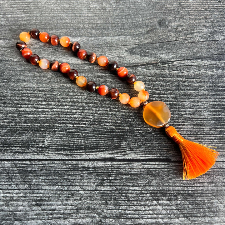 Orange and amber bead meditation mala with dark brown accents and orange tassel