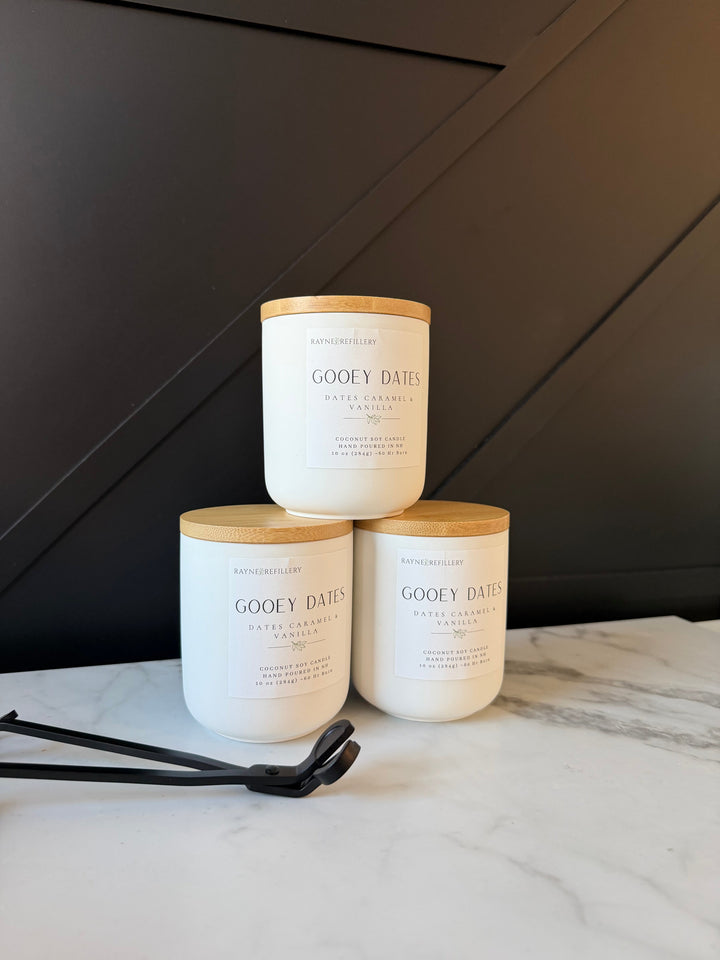 Three Gooey Dates vanilla coconut soy wax candles in white jars with tan lids.