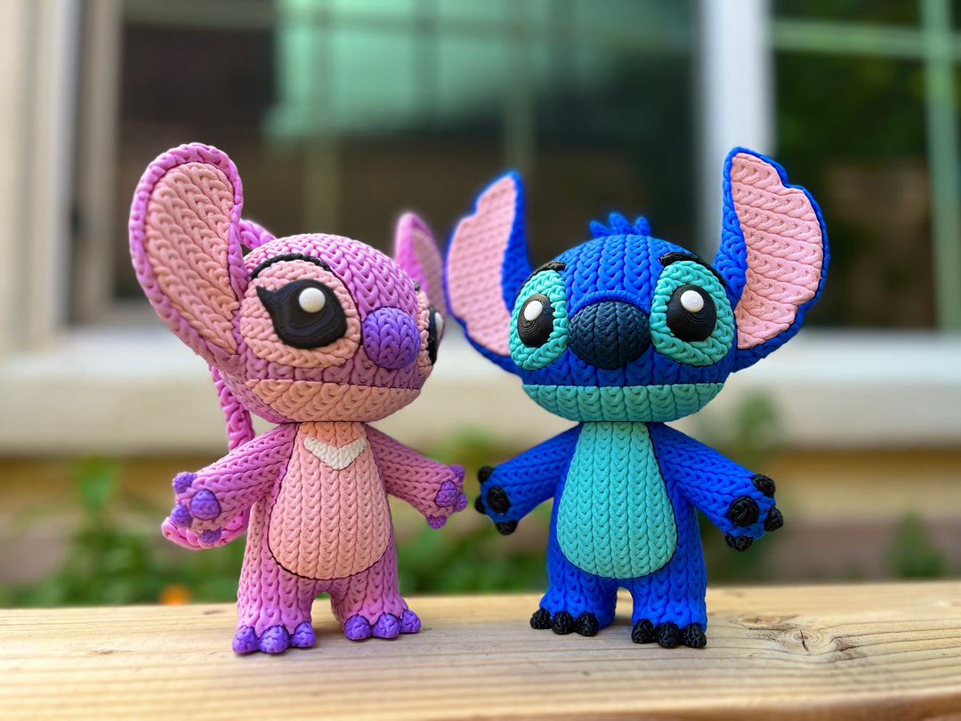Two knitted plush character dolls, one pink and one blue, with large ears and big eyes