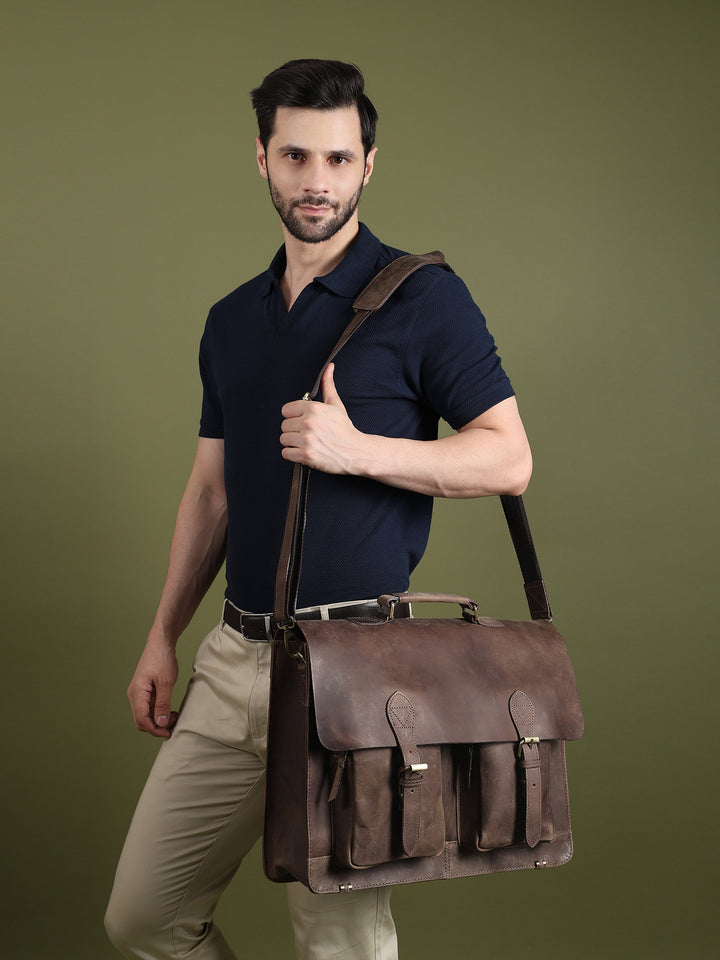Brown leather messenger bag worn on shoulder with flap front and pocket details