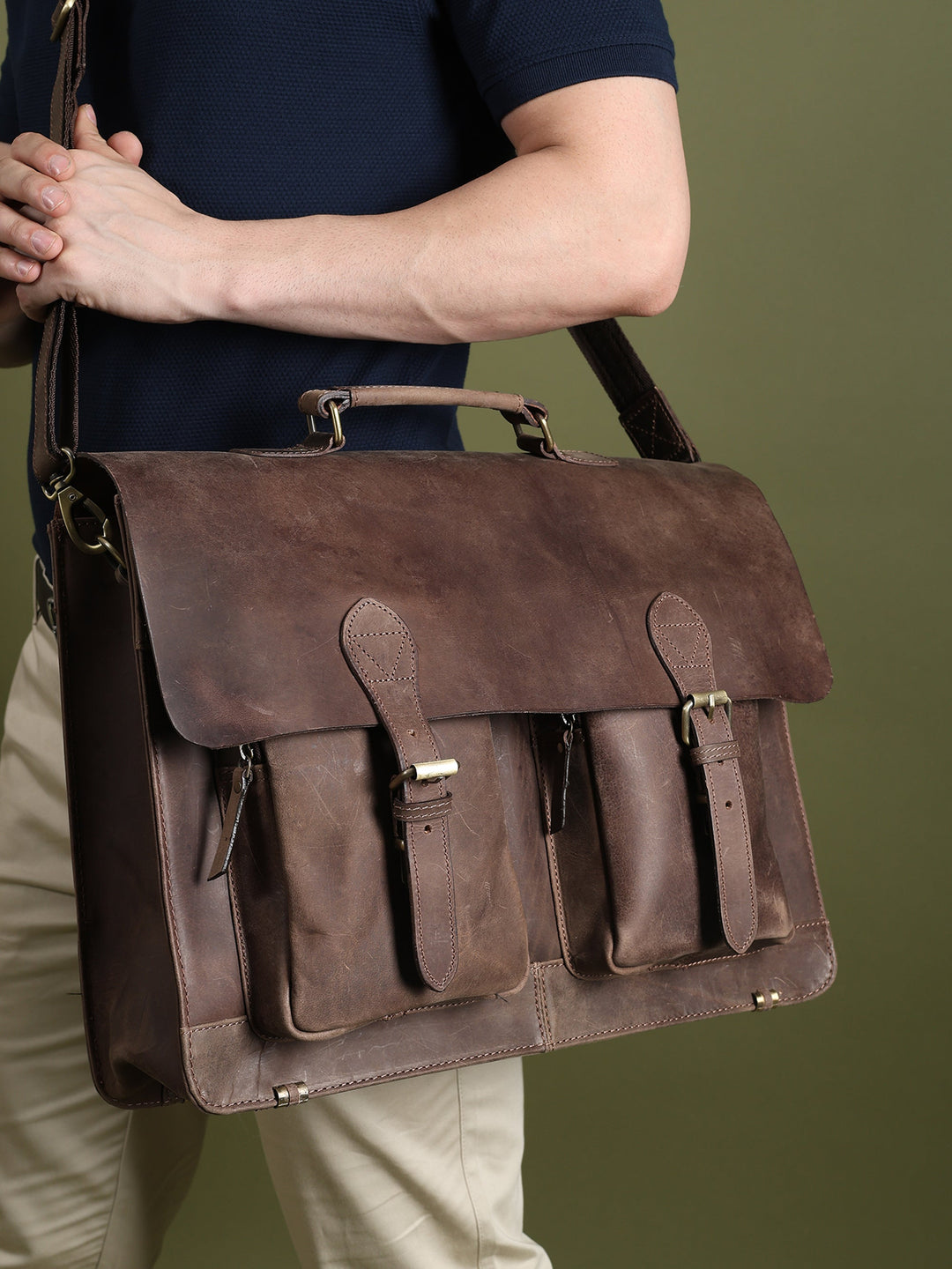 Brown leather messenger bag worn across the body with flap and front compartment pockets