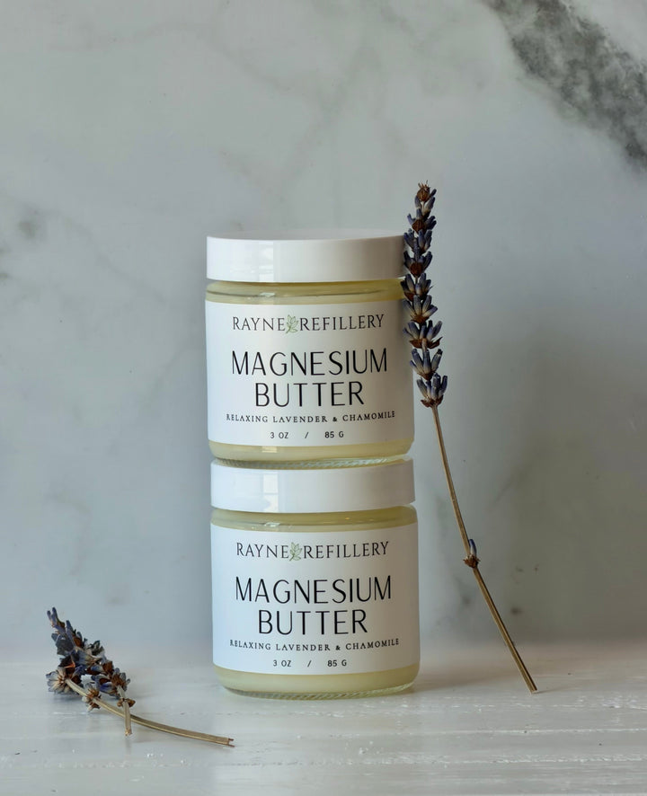 Magnesium butter skincare jars, two stacked with white lids and beige label