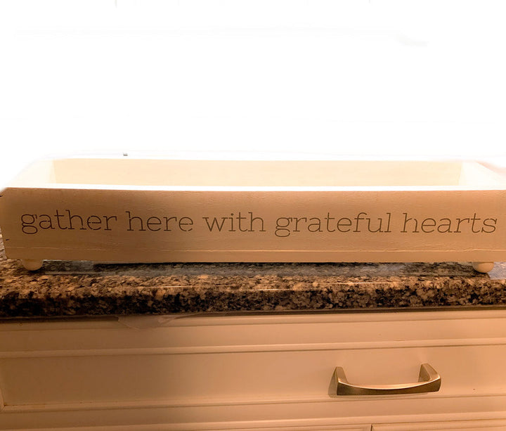 Long wooden tray with 'gather here with grateful hearts' lettering on front