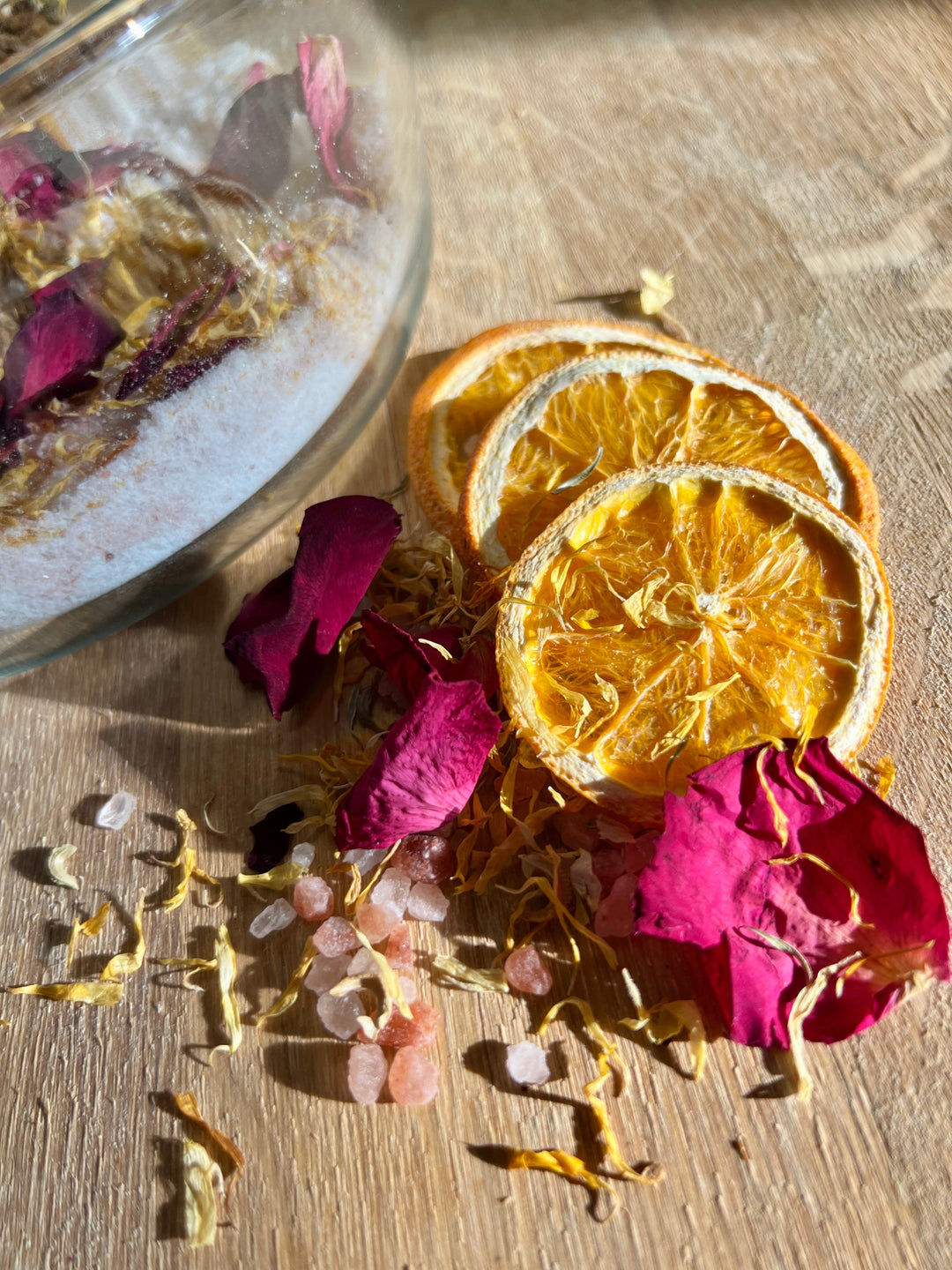 Loose bath salts with dried rose petals and orange slices