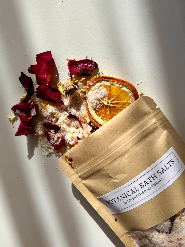 Kraft pouch of botanical bath salts with dried rose petals and citrus slice
