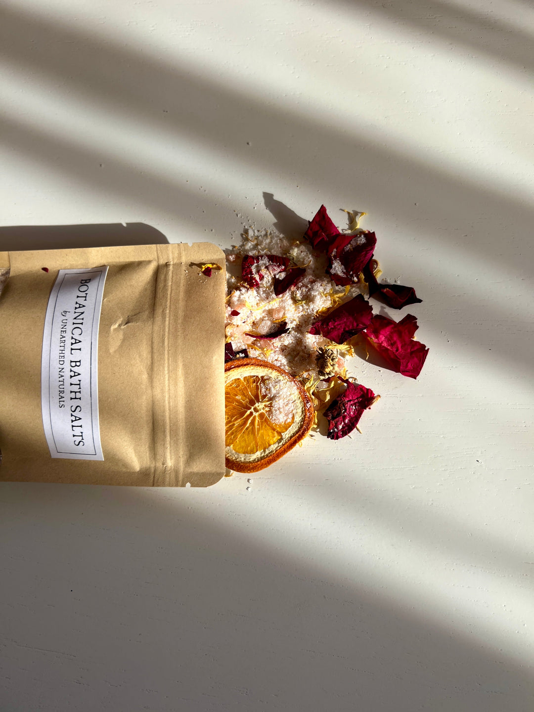 Side view of botanical bath salts pouch with dried petals and orange slice