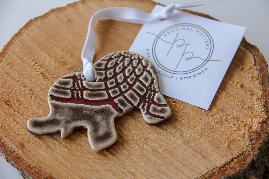 Grey patterned elephant ornament on wood slice with white hanging ribbon and tag