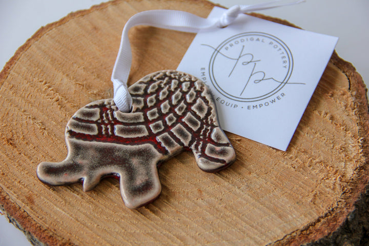 Grey patterned elephant ornament on wood slice with white hanging ribbon and tag