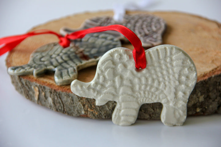 White elephant ornament with red ribbon tie and grey patterned elephant behind