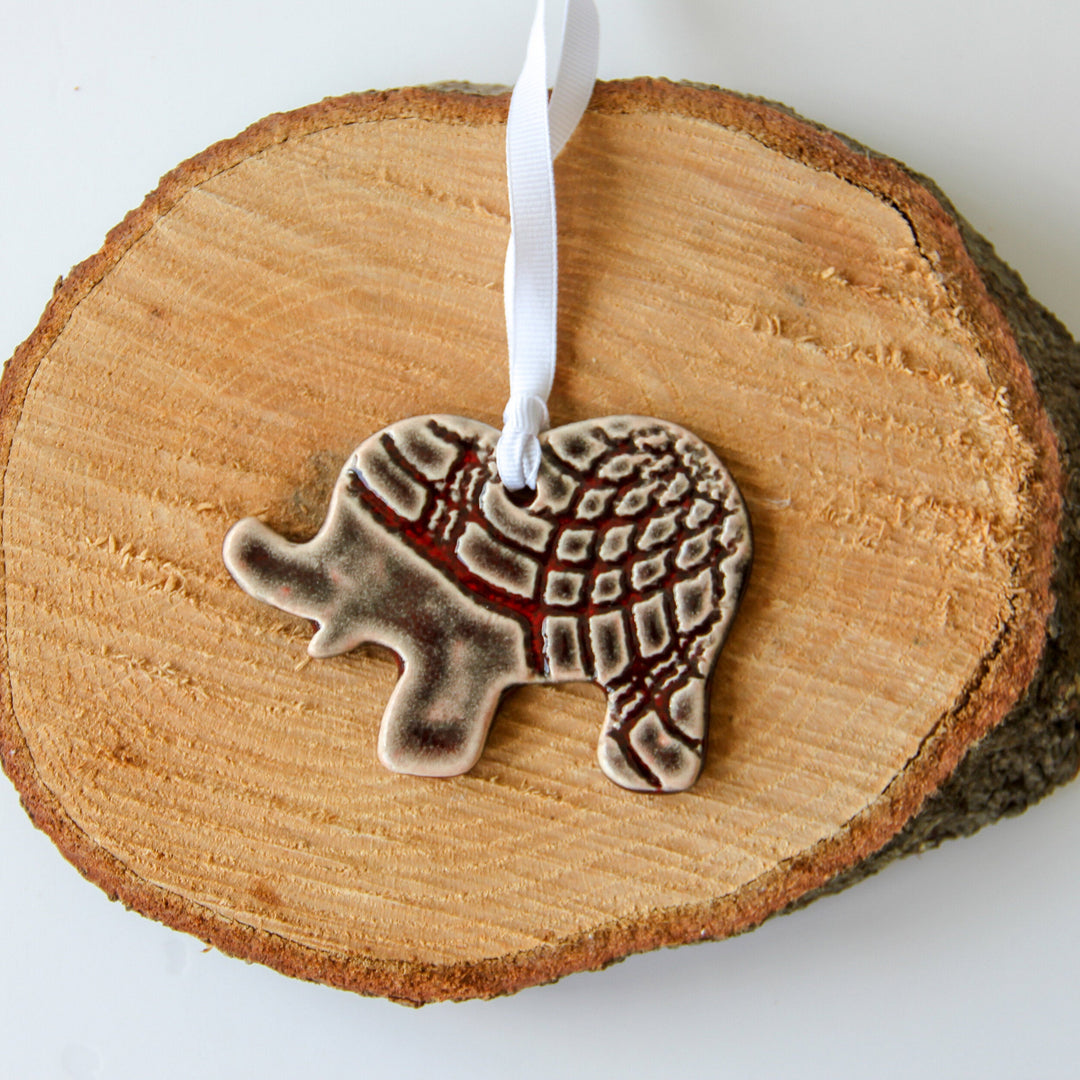 Grey patterned elephant ornament centered on wood slice with white hanging ribbon