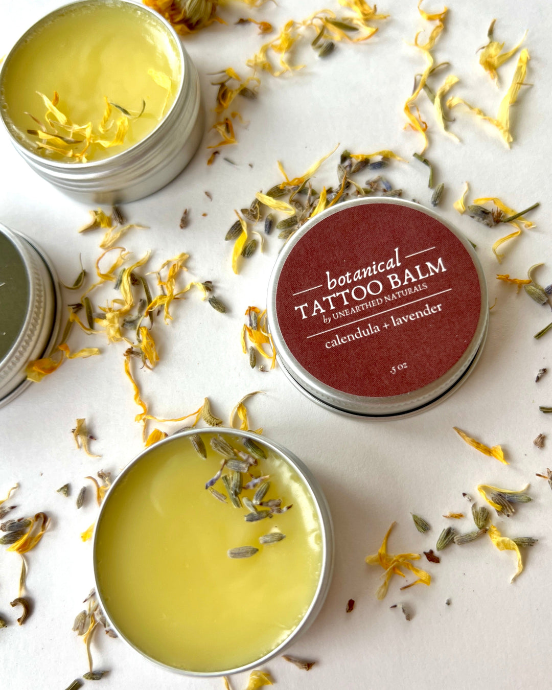 Close-up of yellow salve tin and red-labeled tattoo balm tin