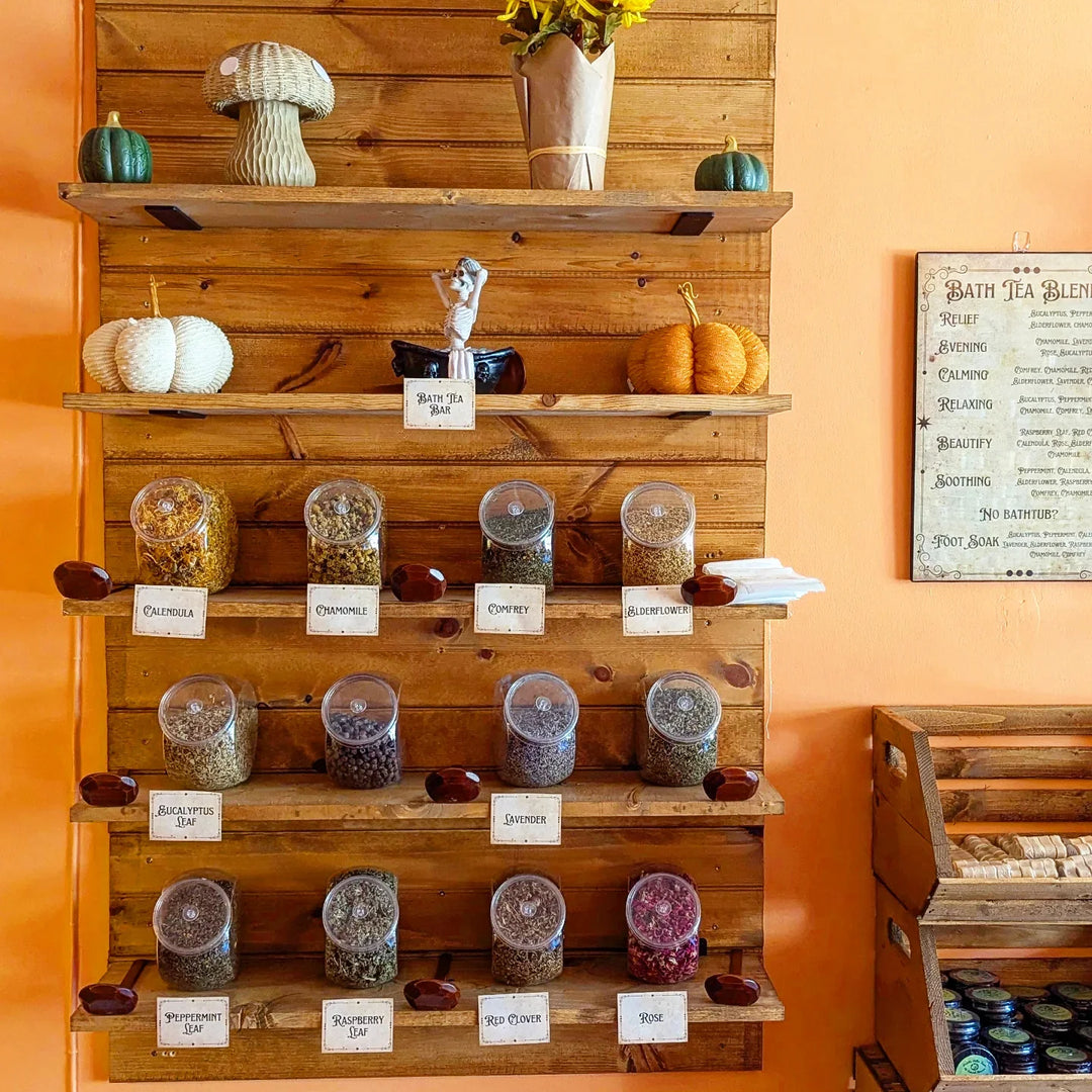 Wooden shelf with labeled bath tea jars, assorted blends and sizes.