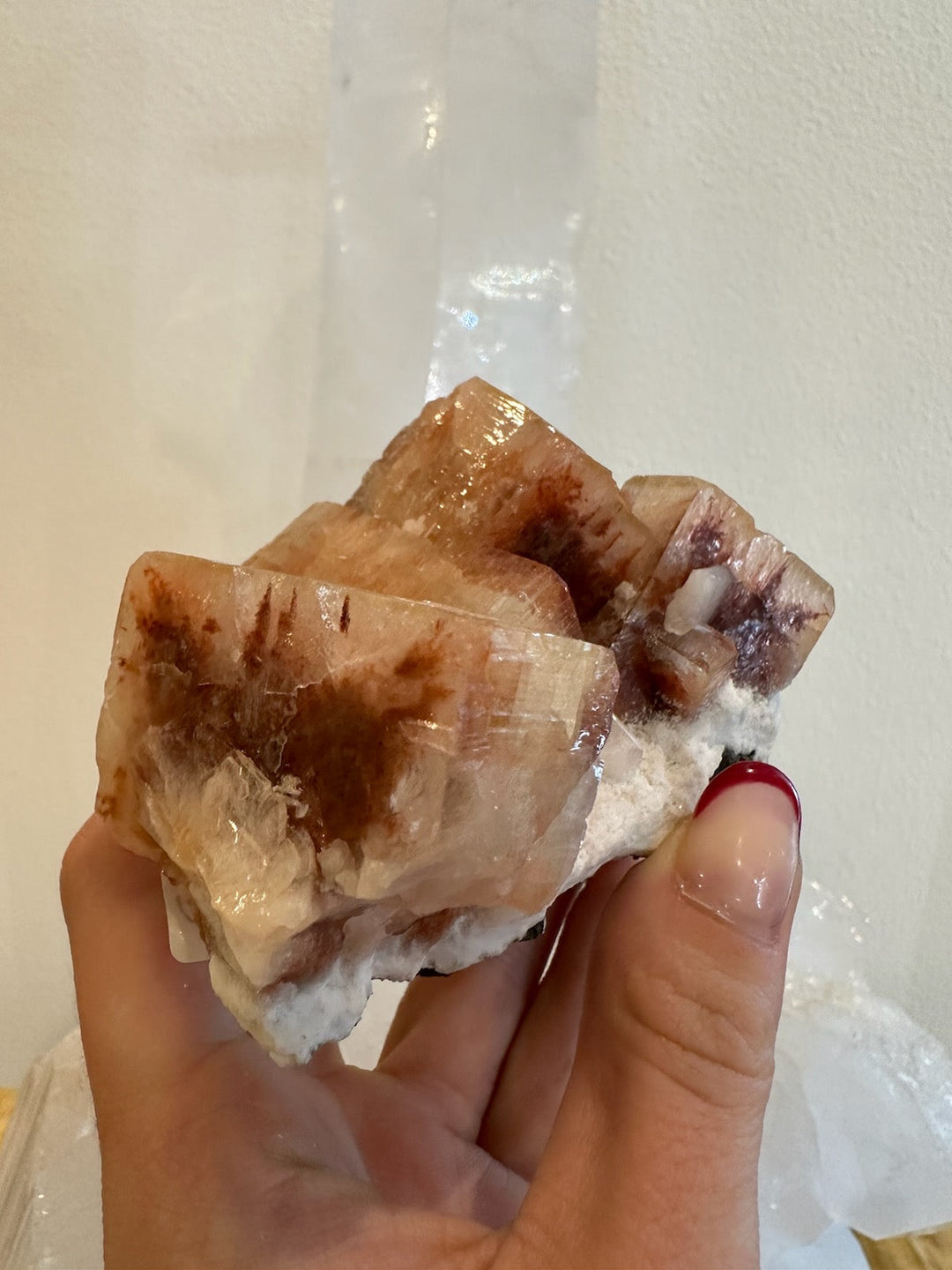 Red-orange apophyllite crystal cluster on white rock matrix, angled view