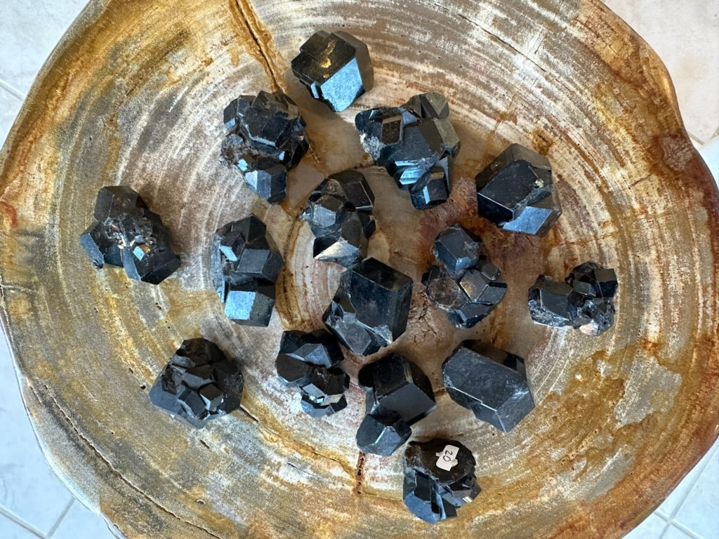 Melanite garnet crystal cluster in bowl: dark black cubes with blue sheen