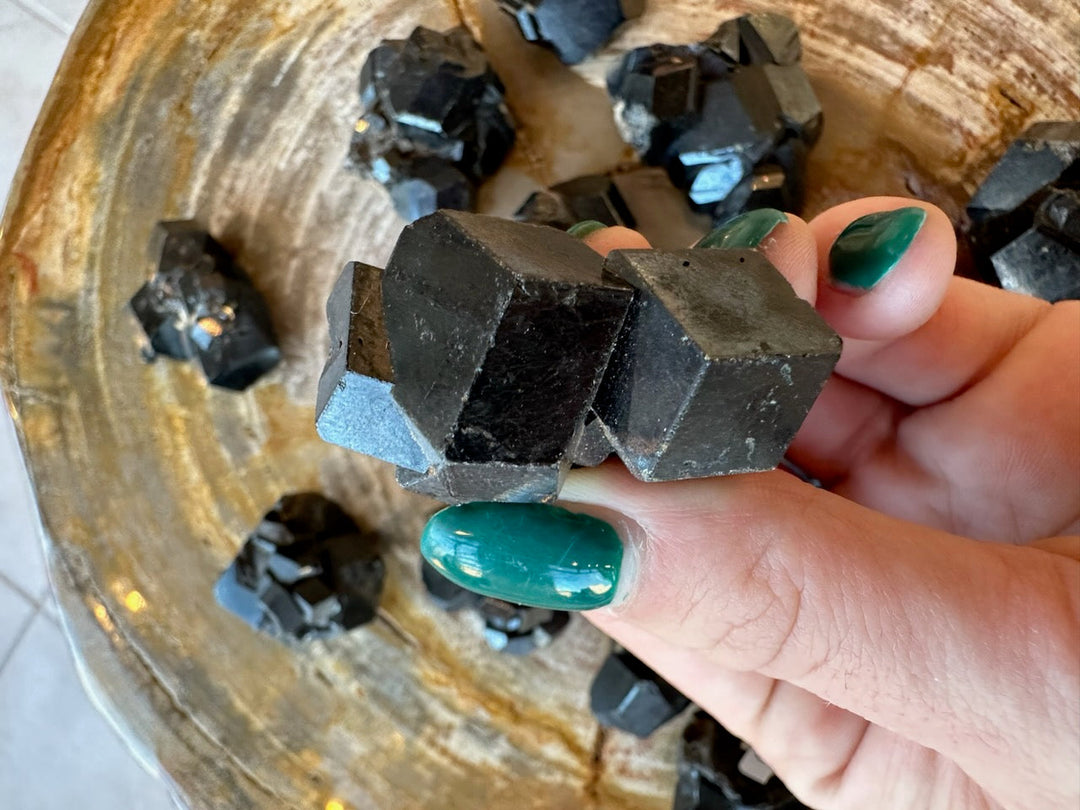 Melanite garnet crystal cluster held close: matte black cubes with metallic blue flashes