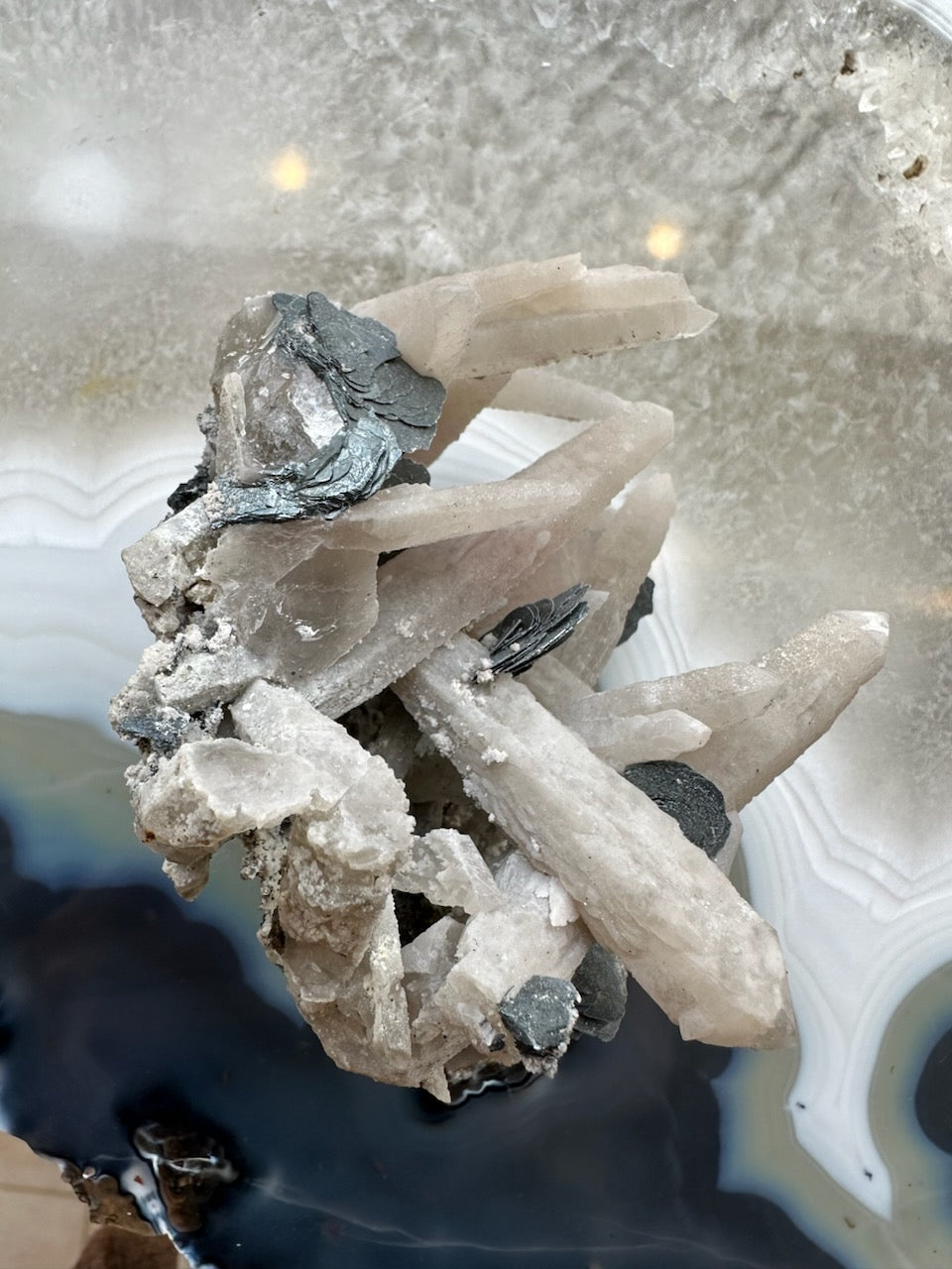 Dogtooth calcite cluster with mica, translucent pale white crystals and dark metallic mica