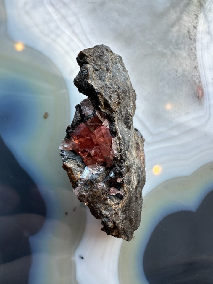 Rhodochrosite crystal cluster on dark rock matrix, red gem points