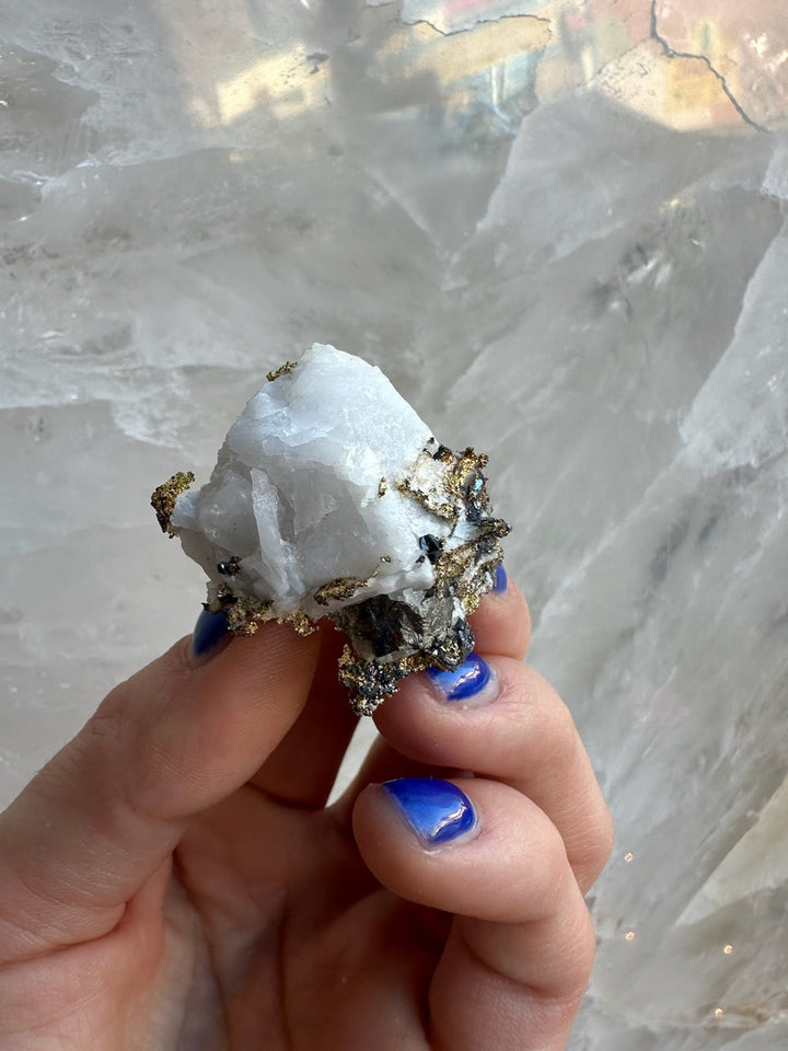 White quartz and golden pyrite mineral specimen held in hand, angled