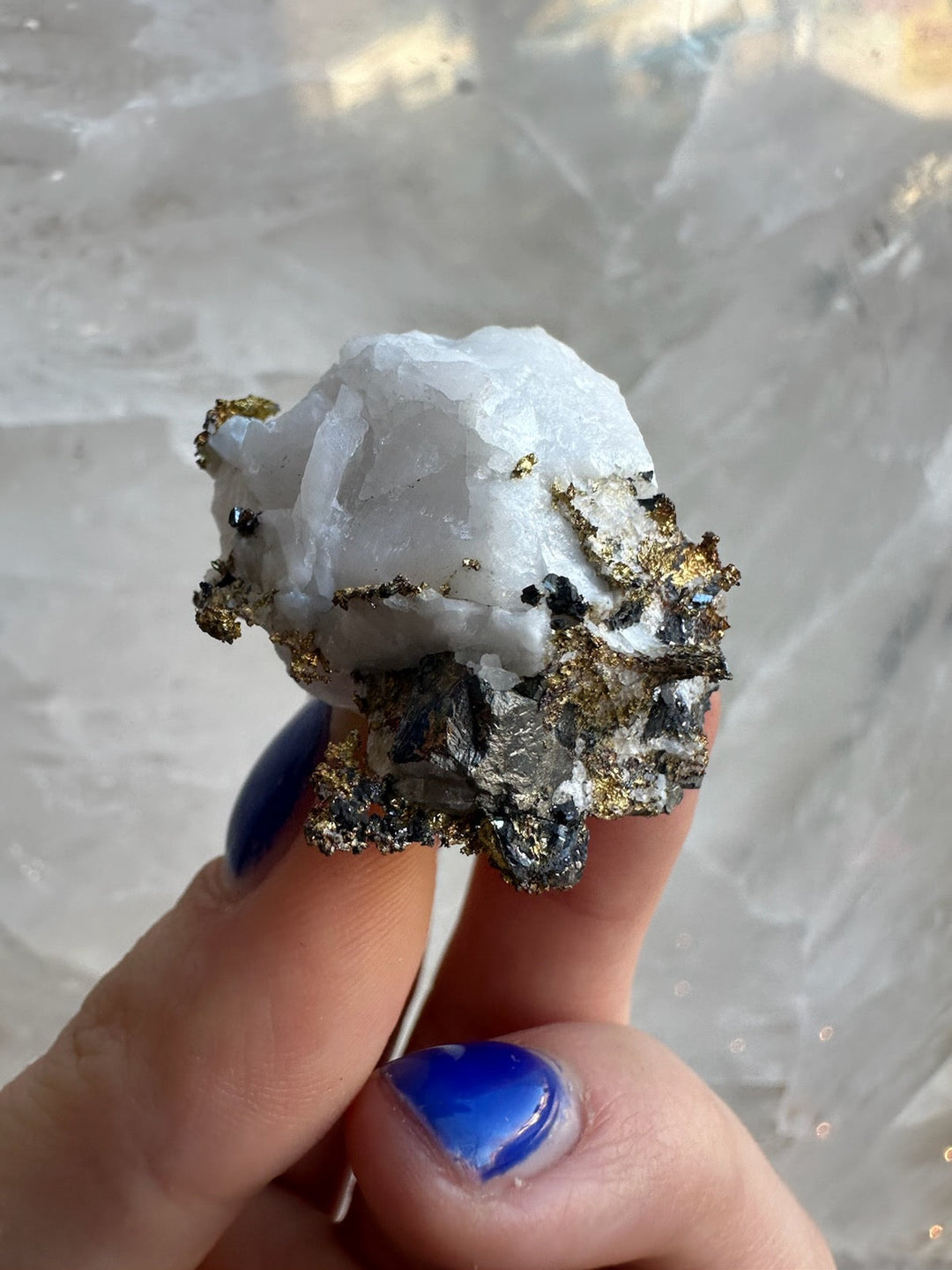 Quartz crystal with golden pyrite mineral specimen held in hand, close-up