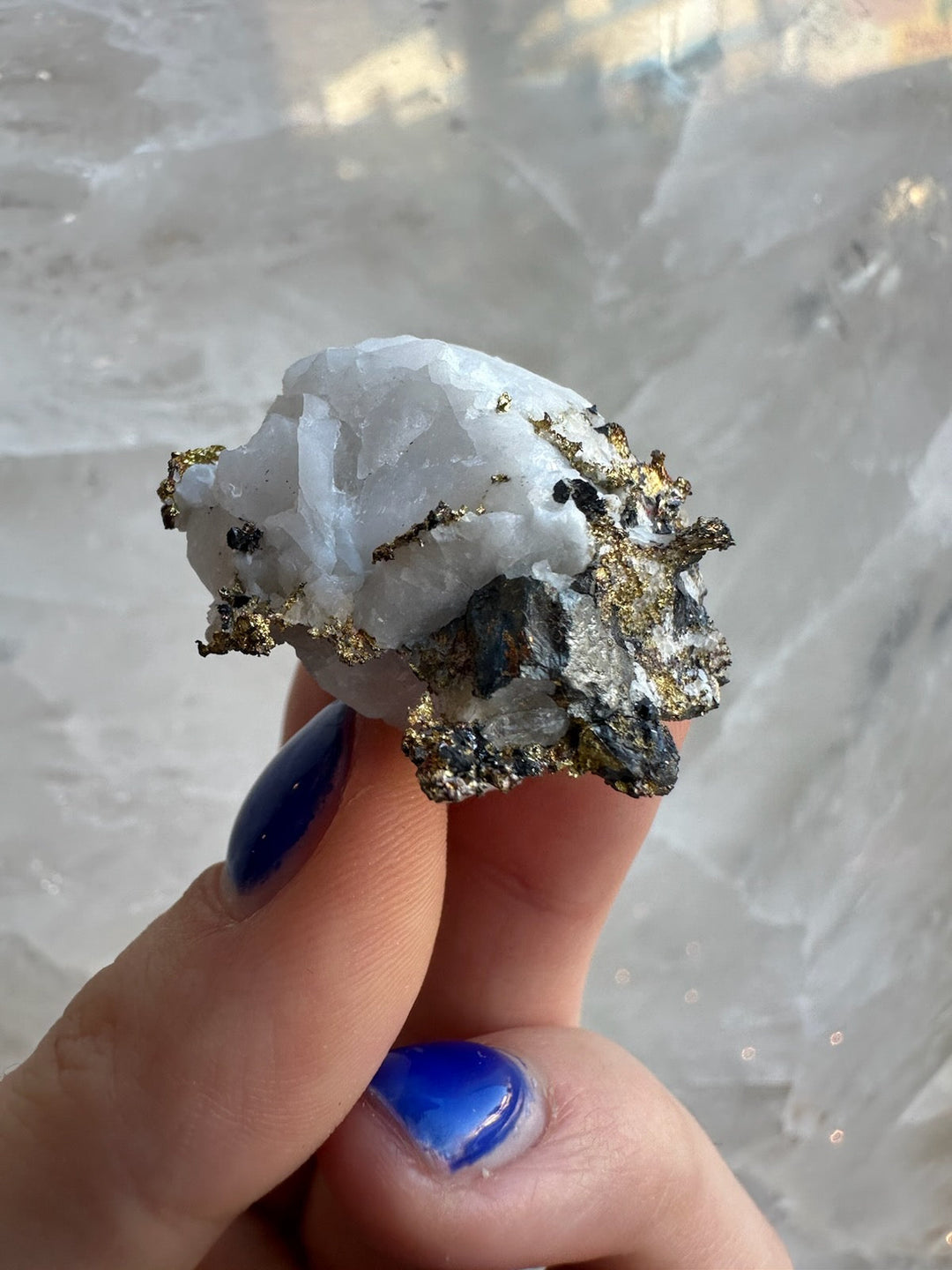 Quartz crystal with golden pyrite mineral specimen held in hand, close-up