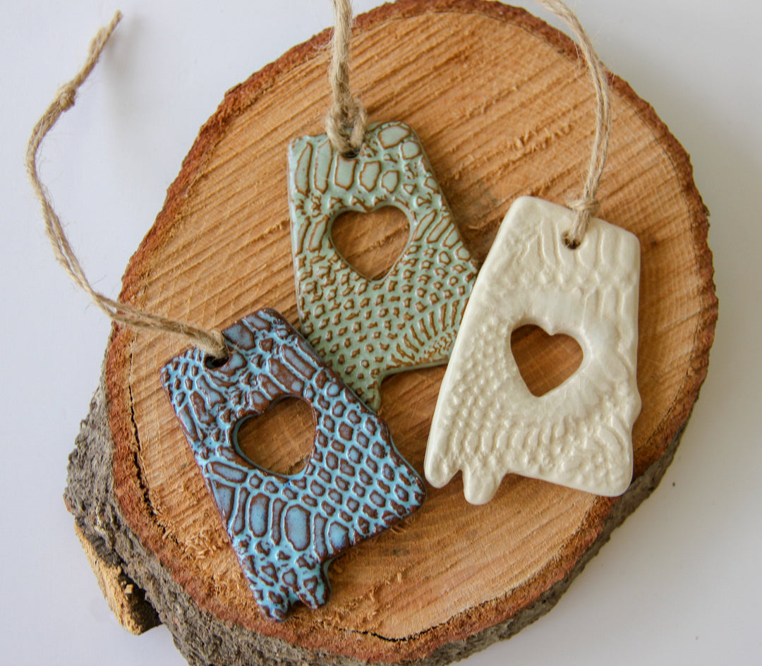 Set of glazed letter A ornaments on wood: blue, gold-green, and white, heart cutouts