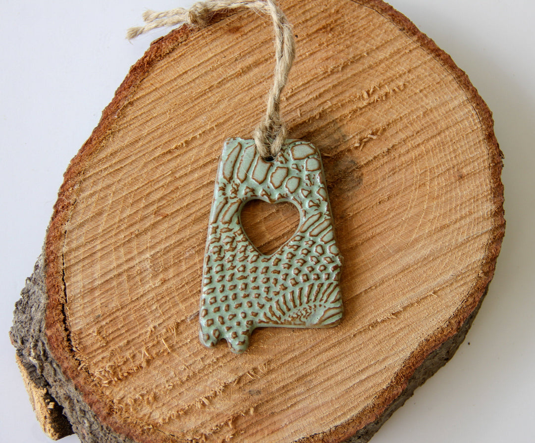 Green glazed letter A ornament with heart cutout, textured pattern, hanging on twine
