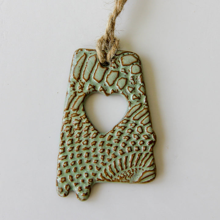 Close-up green glazed letter A ornament with heart cutout and raised textured pattern