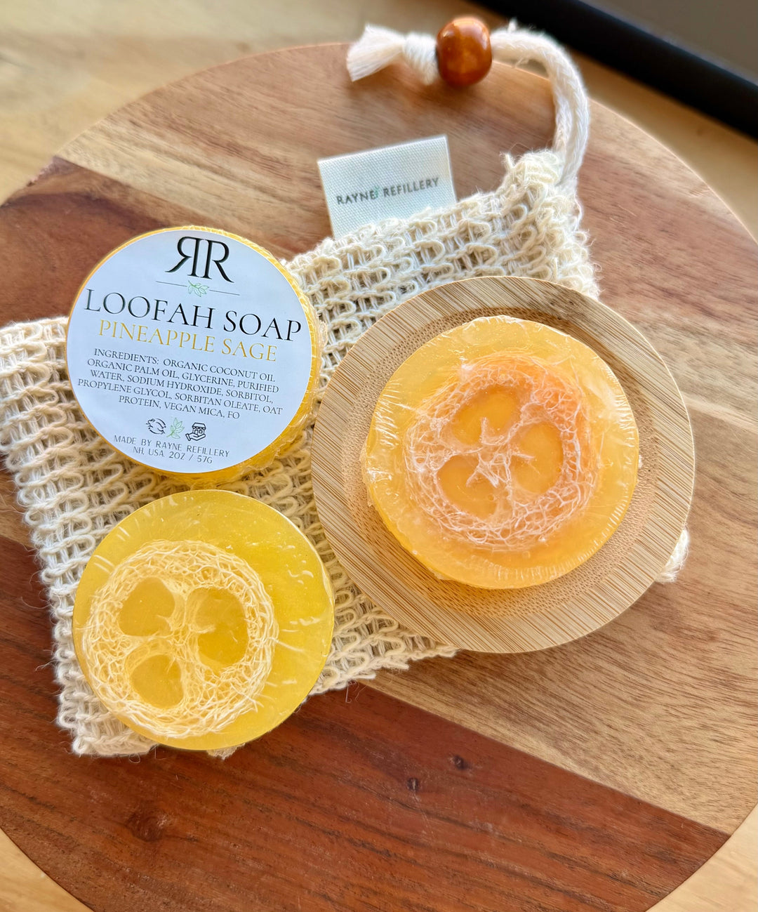 Orange and yellow loofah soap discs with 'Pineapple Sage' scent label on wooden tray