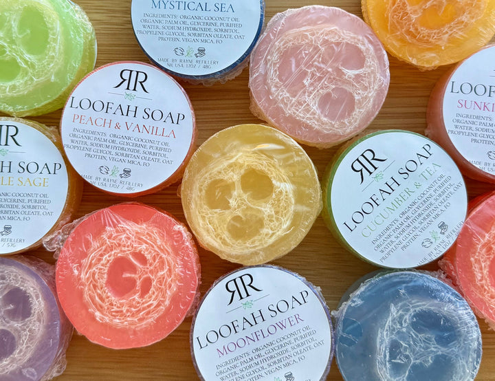 Assorted labeled loofah soap bars, including green cucumber & green tea