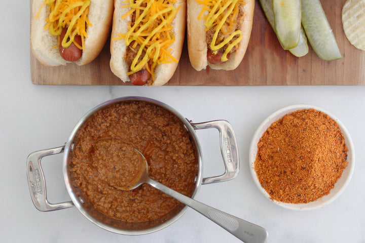 Coney Island hot dog spice blend simmering in a pot with hot dog toppings nearby