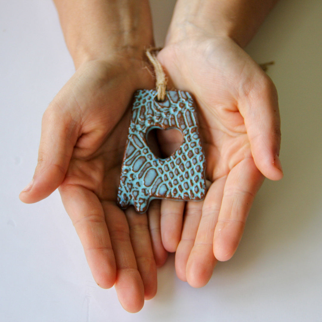 Blue glazed Alabama letter A ornament with heart cutout and textured pattern, hanging twine