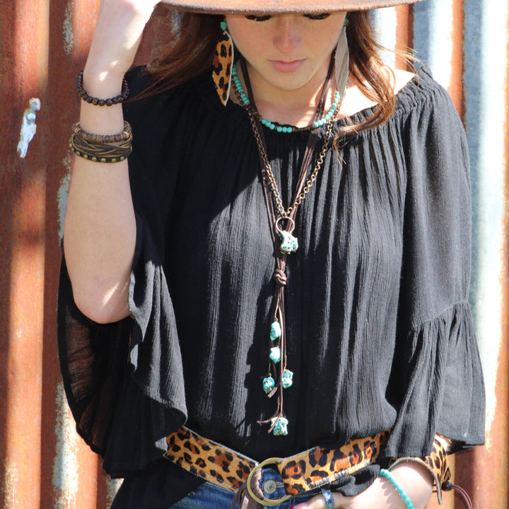Turquoise bead collar necklace with long pendant necklace layers worn at neckline.
