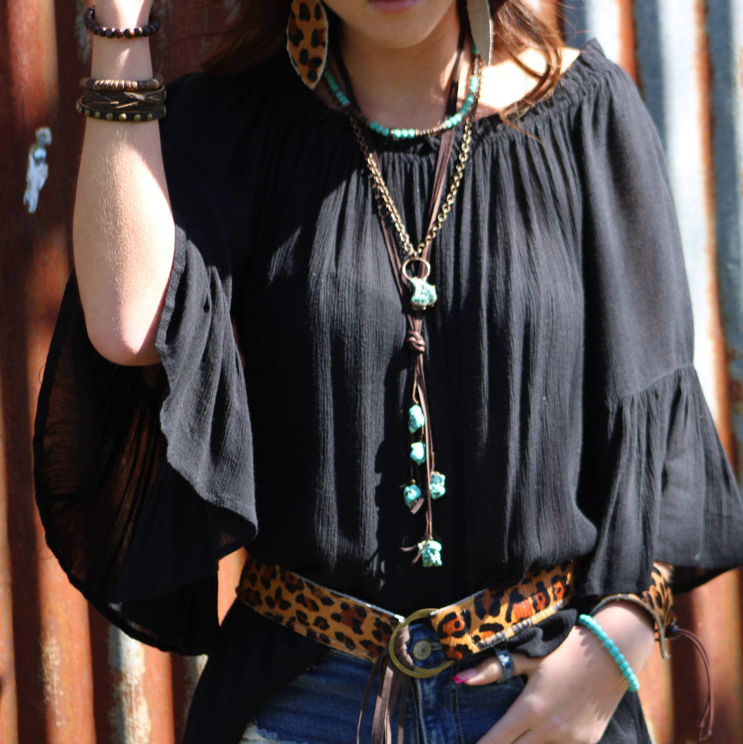 Turquoise bead collar necklace with layered chains and heart pendant worn at neckline.