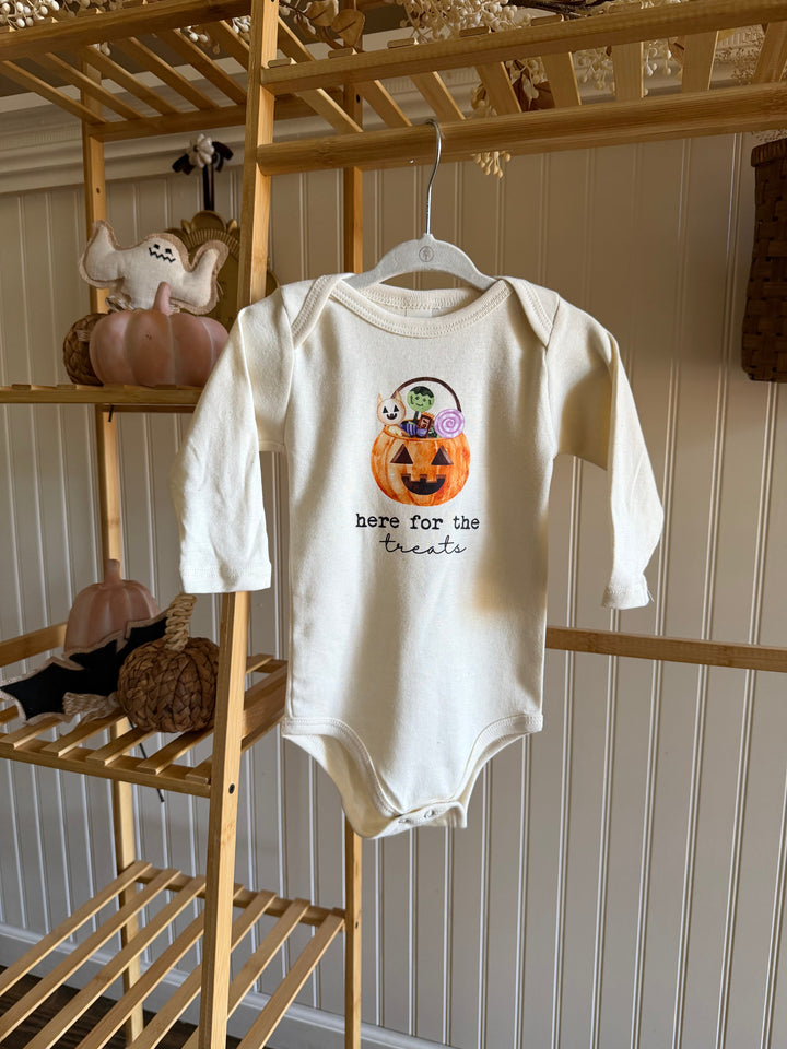 Cream long-sleeve bodysuit with front candy bucket graphic, hanging on a hanger