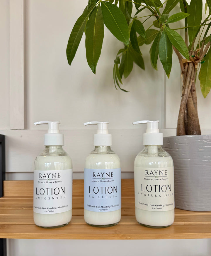Three moisturizing body lotion bottles with pumps and light blue labels, RAYNE brand.