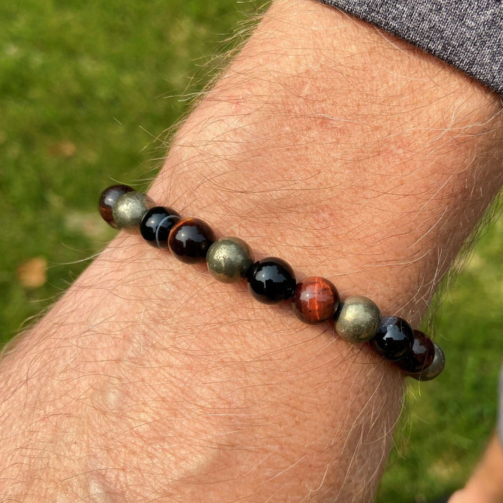 Tiger eye beaded bracelet on wrist with black beads and brown-red stone highlights.
