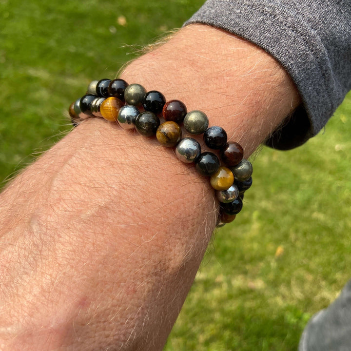 Tiger eye bead bracelet on wrist with dark black beads and gold-brown stone beads.