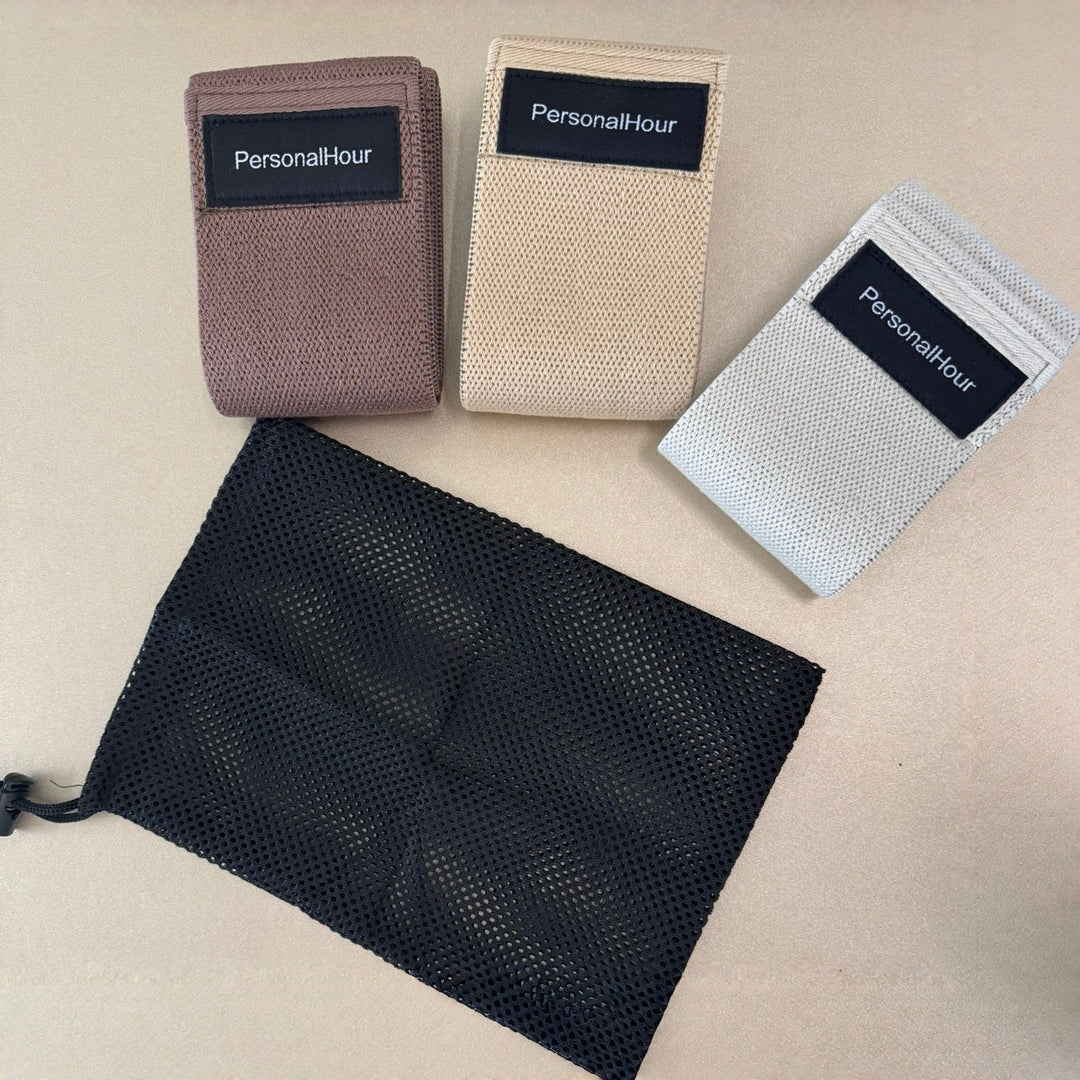 Set of non-slip Pilates bands in beige, mauve, and dark gray/black fabric loops.